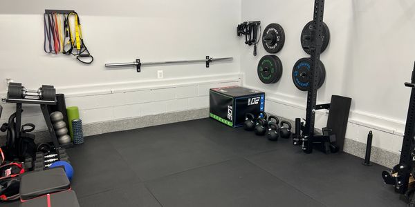 A clean, organized home gym with weights, resistance bands, and a bench.