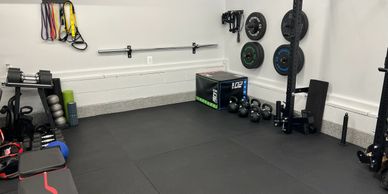 A clean, organized home gym with weights, resistance bands, and a bench.