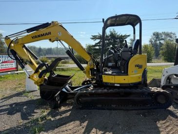 Yellow Yanmar mini excavator on gravel.