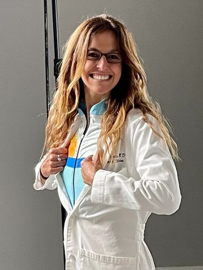 Smiling woman in a white lab coat and glasses.