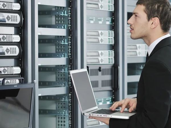 Technician working on servers in a data center with a laptop.