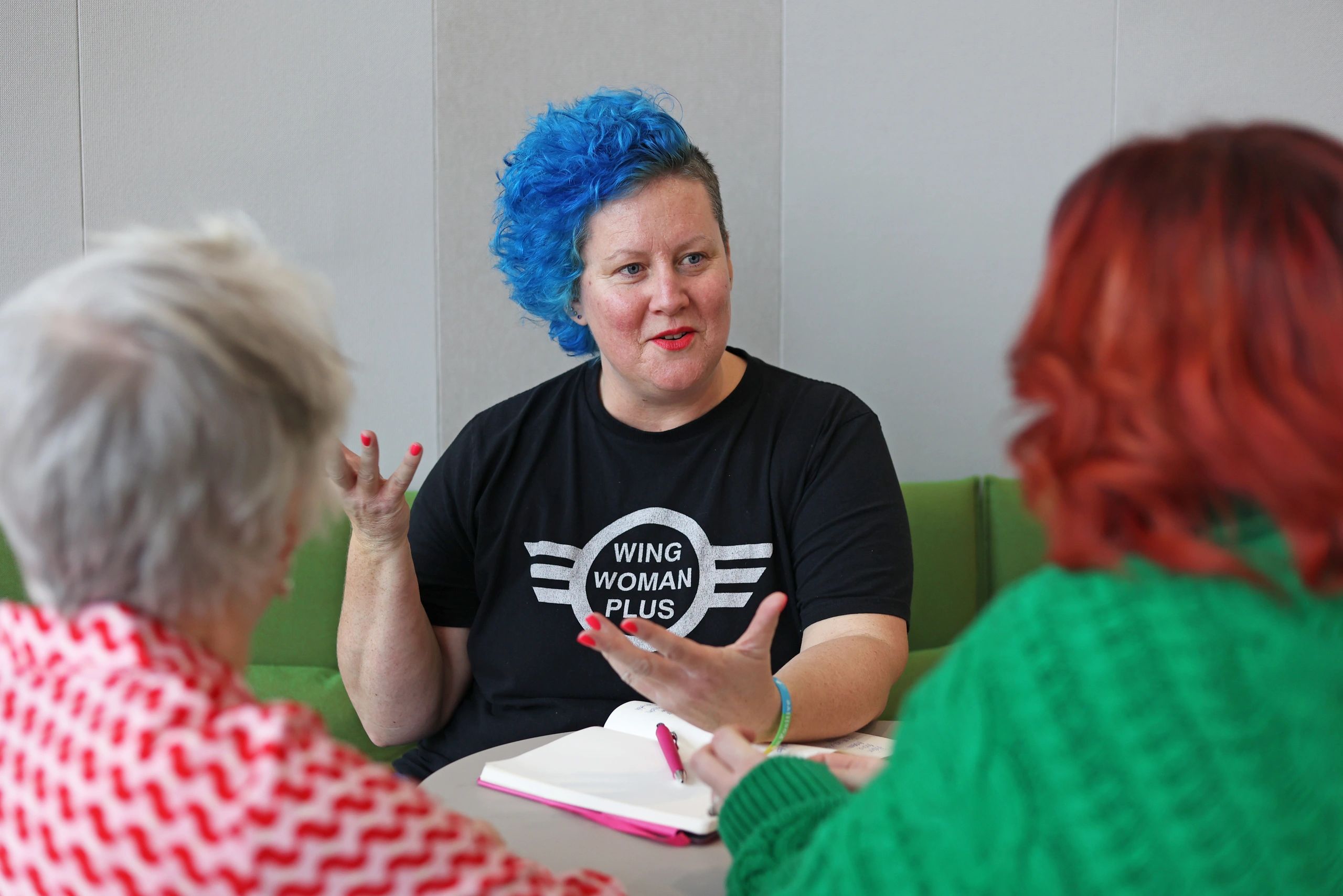 A group of women talking. One facing the camera speaking animatedly 