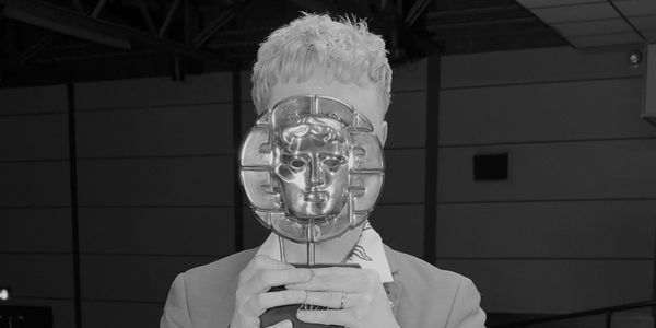 Person holding a BAFTA trophy in front of their face.
