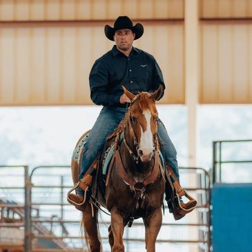 Man in cowboy hat riding a horse indoors.