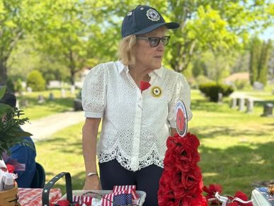 Woman stands behind a patriotic-themed table with red, white, and blue decorations.