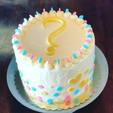 Gender reveal cake with question mark and pink, blue decorations.