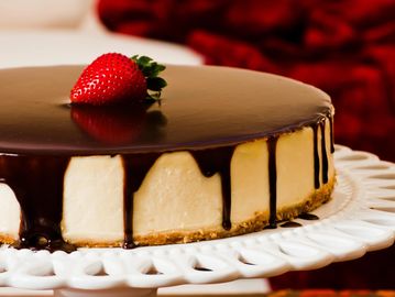 Cheesecake with chocolate glaze and strawberry on top.
