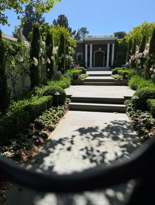 Elegant garden pathway leading to a grand house entrance with columns.