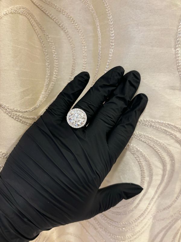 Hand with a large, sparkling Bella Andrea & Co. diamond ring wearing a black glove.