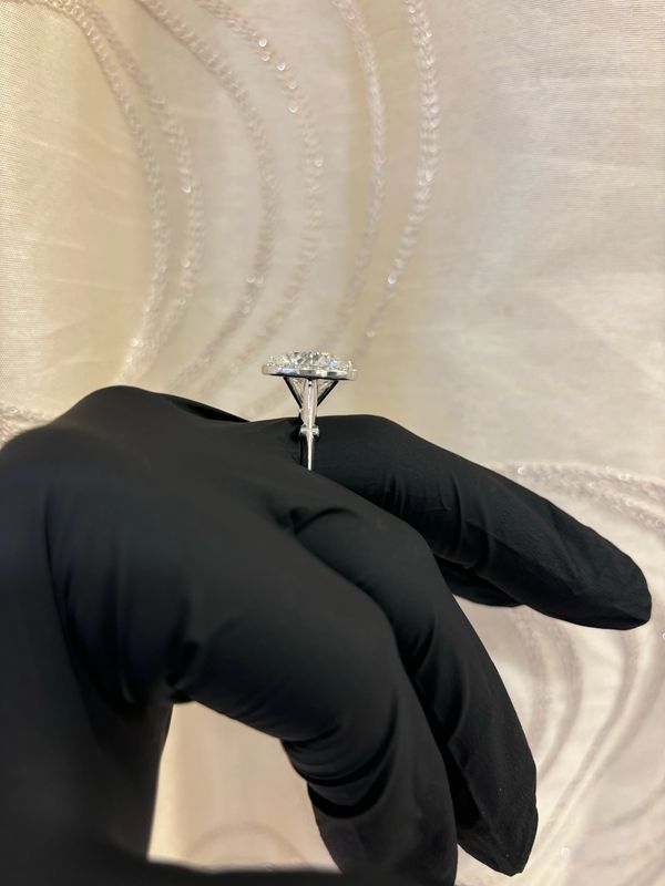 Black-gloved hand holding a Bella Andrea & Co. diamond ring.