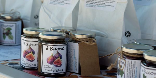 Jars of è Buono dark fig jam displayed on a table.