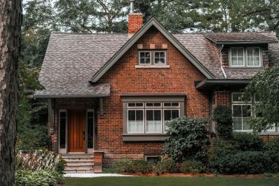 Cozy brick house surrounded by greenery and trees.