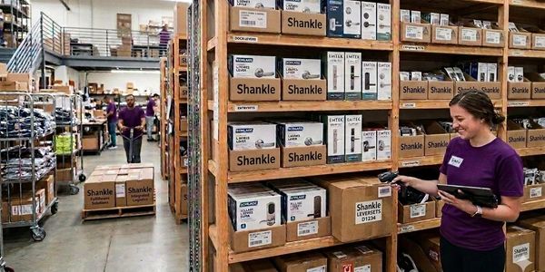 Warehouse worker scanning products on shelves labeled 'Shankle'.