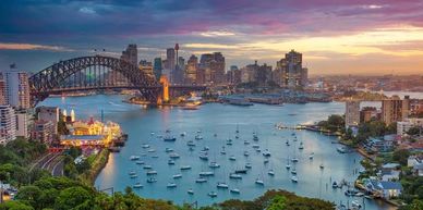 Sunset view of Sydney Harbour with boats and city skyline.