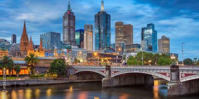 City skyline with a river and bridge at dusk.