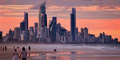 Sunset over a city skyline with people on the beach.