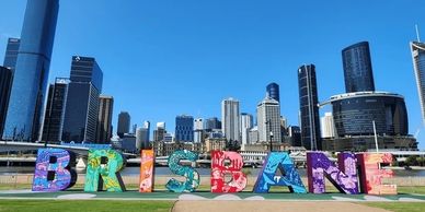 Colorful Brisbane sign with city skyline and clear blue sky in the background.