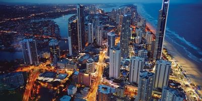 Night aerial view of a coastal city with tall buildings and illuminated streets.