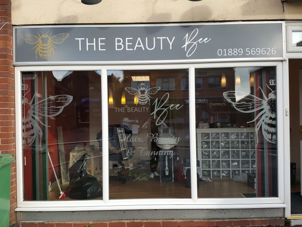 A front of a store with printing on the glass and a sign