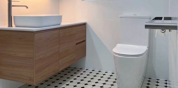Modern bathroom with wooden vanity, white sink, and patterned tile floor.
