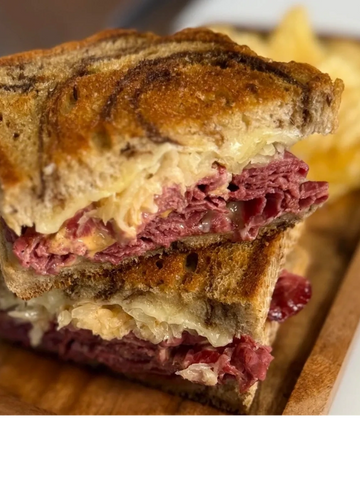 Close-up of a grilled Reuben sandwich with corned beef and sauerkraut.
