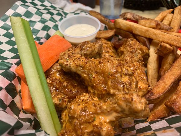 Fried chicken wings with a side of french fries, celery, carrots and ranch to dip