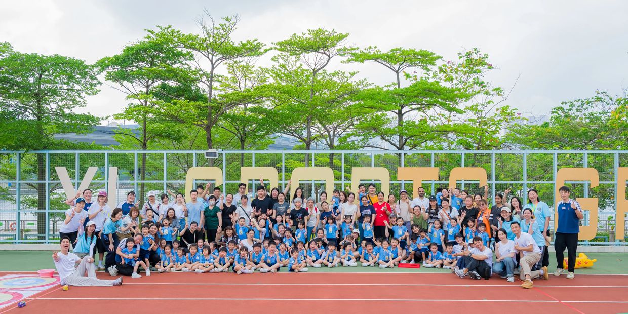 Large group of children and adults posing together outdoors on a sports field.