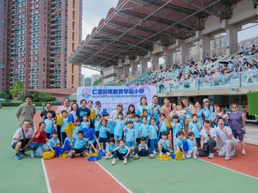 Group photo of children and adults at an outdoor sports event with a banner in Chinese.