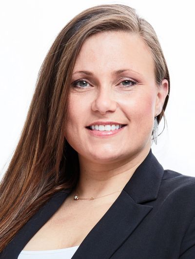 Confident woman with long hair smiling, wearing a black blazer and white top.