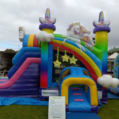 Colorful unicorn-themed inflatable slide at an outdoor event.