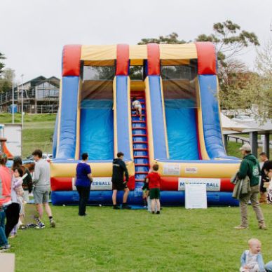 Children playing on an inflatable slide at a park event.