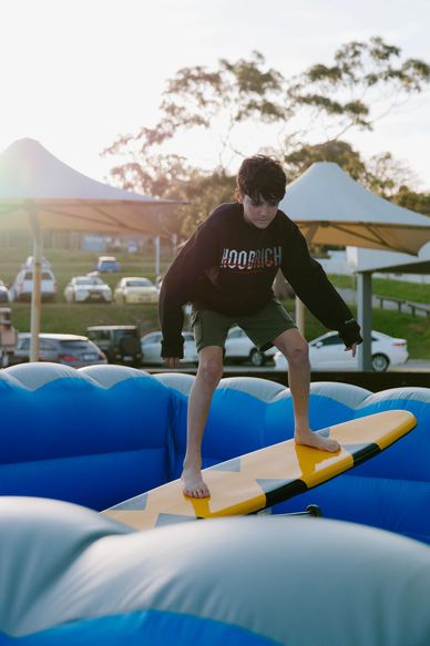 Boy balancing on a surfboard in an inflatable pool.