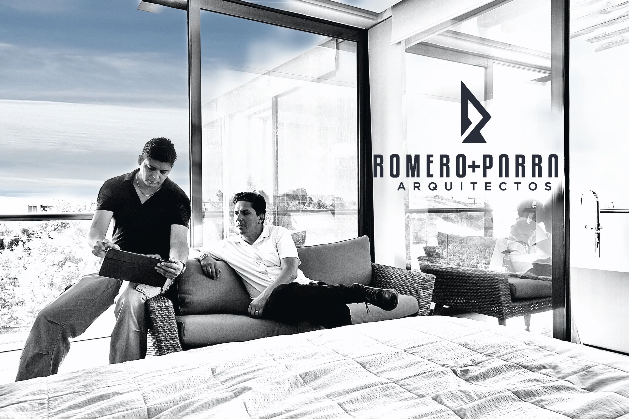 ARQUITECTOS CONSTRUCTORES  PROYECTO ARQUITECTÓNICO, SENTADOS SOBRE UN SILLÓN UTILIZANDO UN IPAD