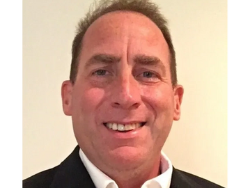 Smiling man in a suit jacket and white shirt.