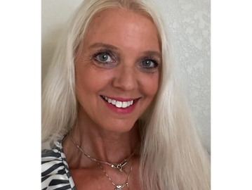 Smiling woman with long blonde hair and layered necklaces.