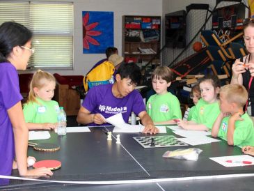 Group of children and adults around a table playing games.