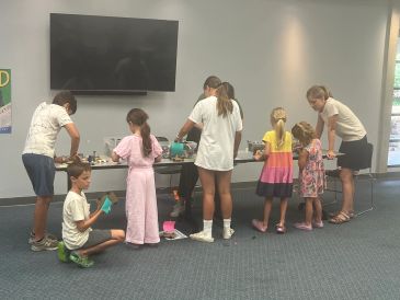 Children and an adult engaging in a group activity at a table.