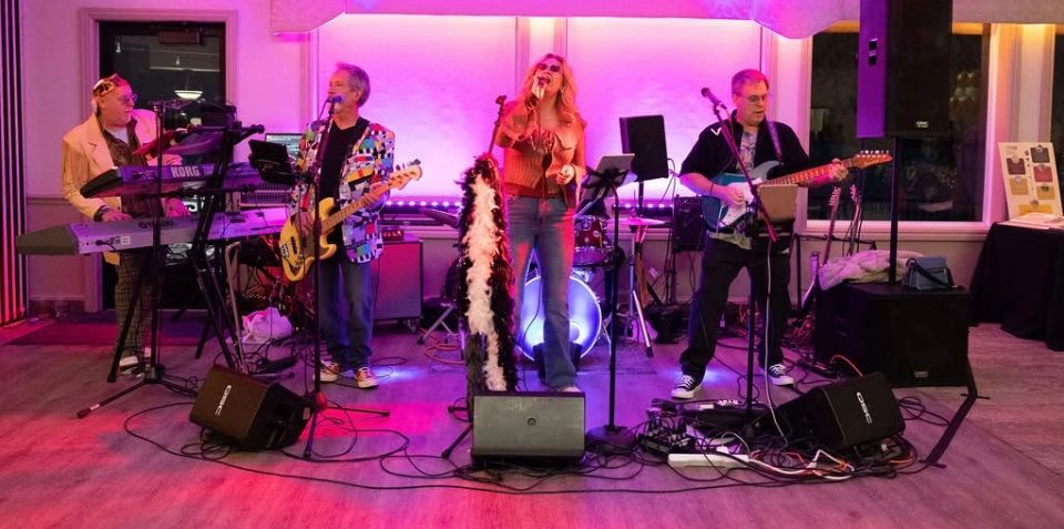A band performs on stage with vibrant purple lighting and instruments.