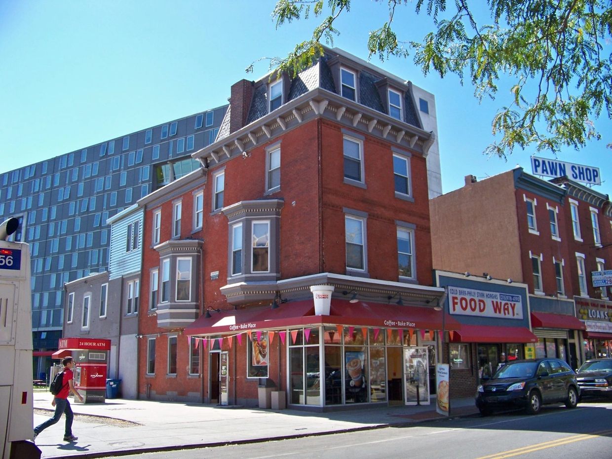 Street corner with a coffee shop, food market, and pawn shop on a sunny day.
