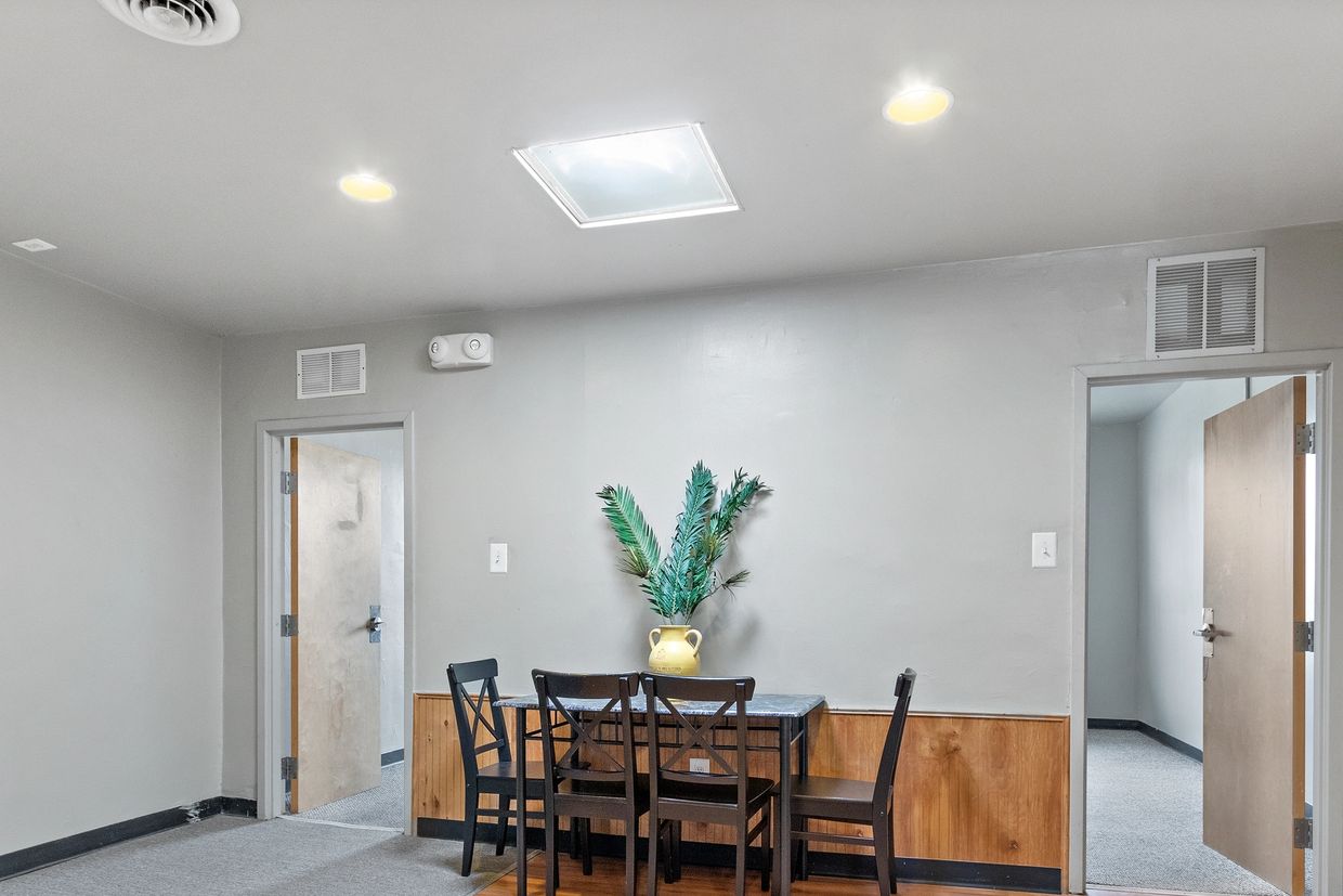 Minimalist room with a small dining table and chairs under bright ceiling lights.