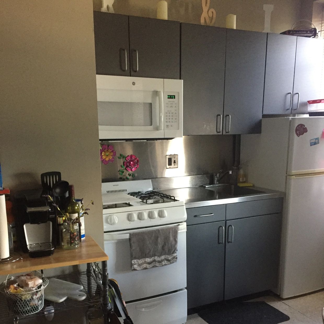 Compact kitchen with white appliances and dark cabinets.
