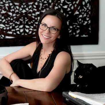 Jennifer Hall, intuitive counselor and coach, seated beside a black cat in a calm, welcoming space.