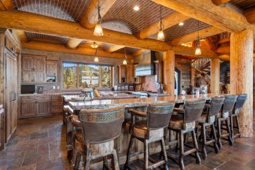 Rustic kitchen with wooden beams and a large island with bar stools.
