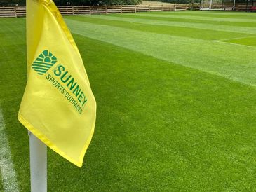 Yellow corner flag on a well-maintained sports field with striped grass.