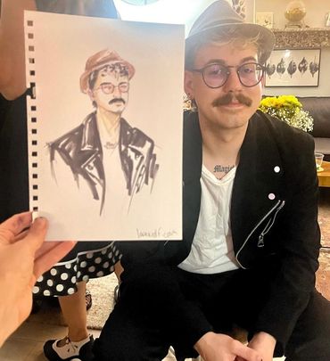 A man poses next to a hand-drawn portrait of himself.