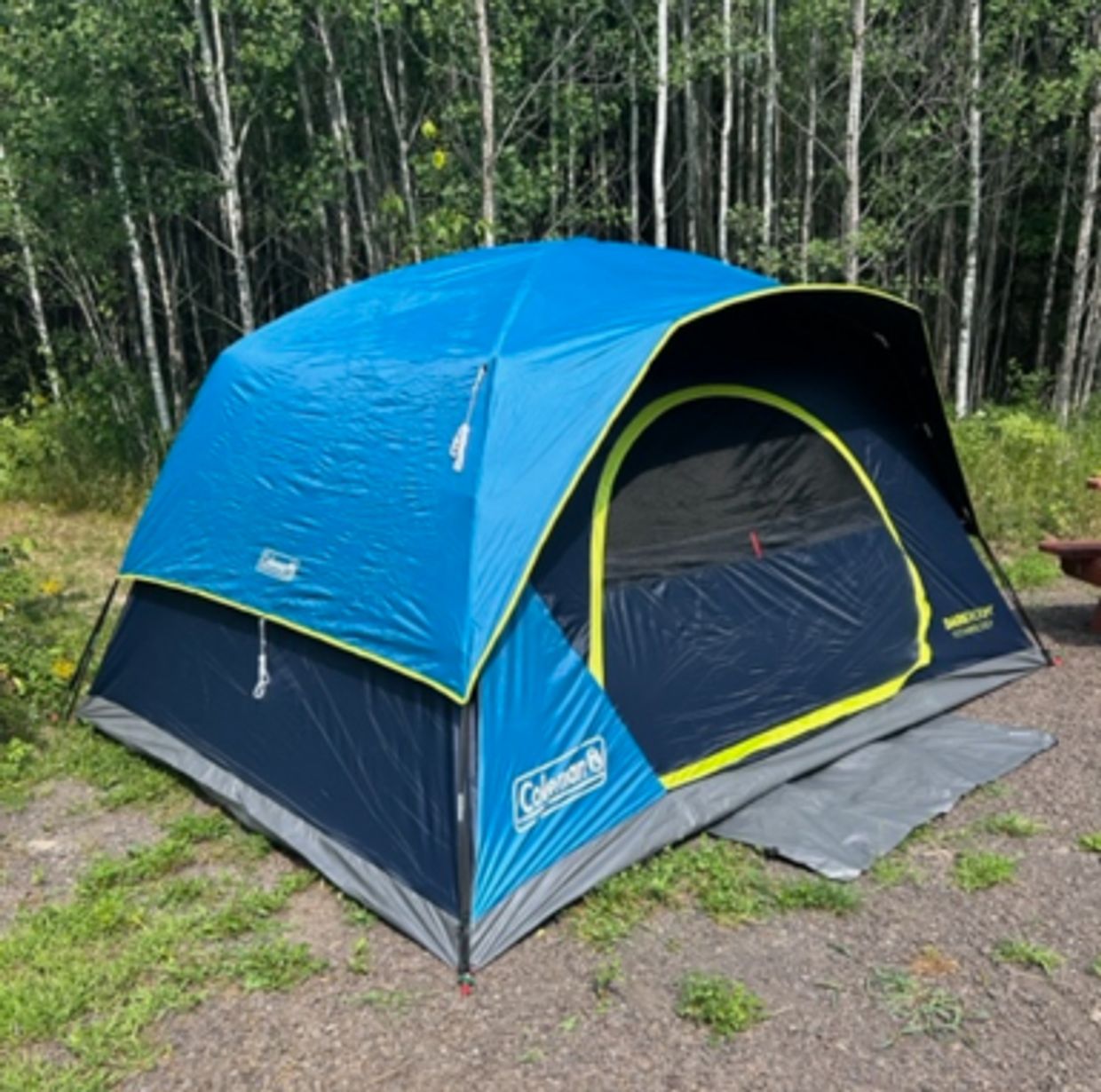 Blue and black Coleman camping tent set up outdoors.