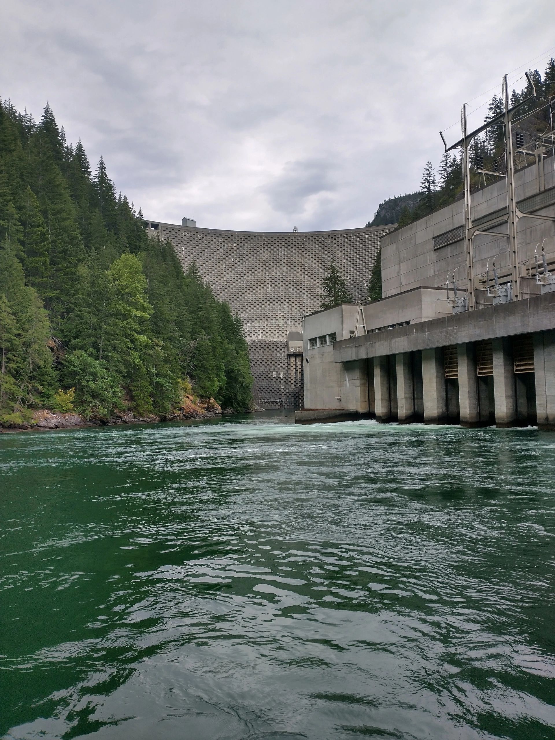 Large dam structure surrounded by forest and water.