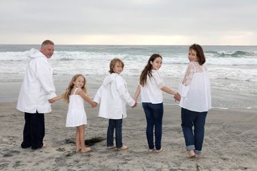 Family beach photo session with family of 5 holding hands walking to ocean.