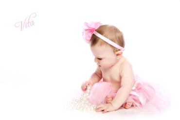 Children's Portrait of a baby girl in a pink ballet tutu with pearls and pink headband on white 