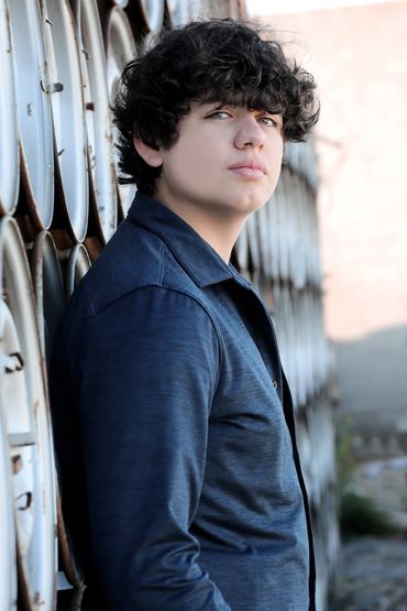 Senior photo of a male leaning against a wall of tire rims